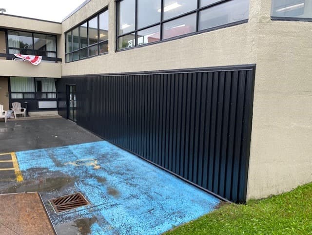Black vertical commercial steel wall cladding along facility courtyard