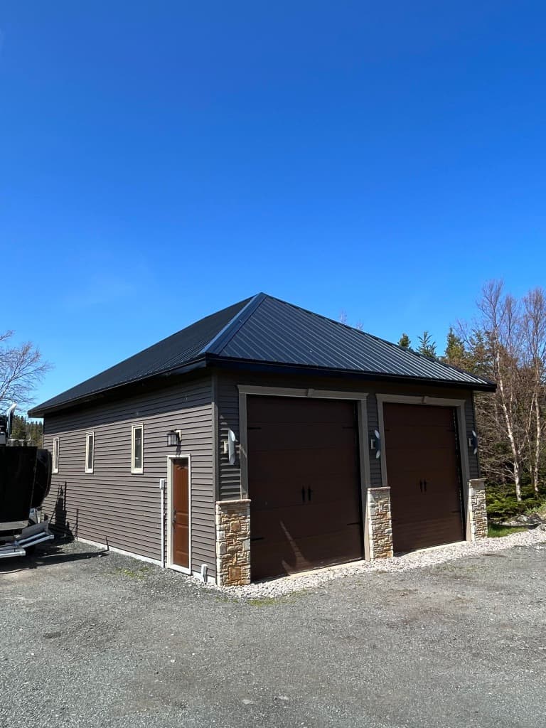 Detached 2-bay garage with black hip metal roof and stone pillars