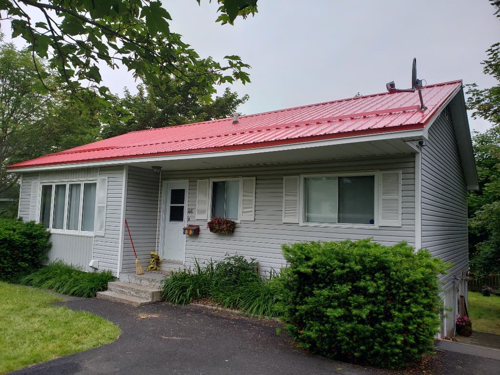 Suburban bungalow with Bright Red metal roof, snow rail, and front garden