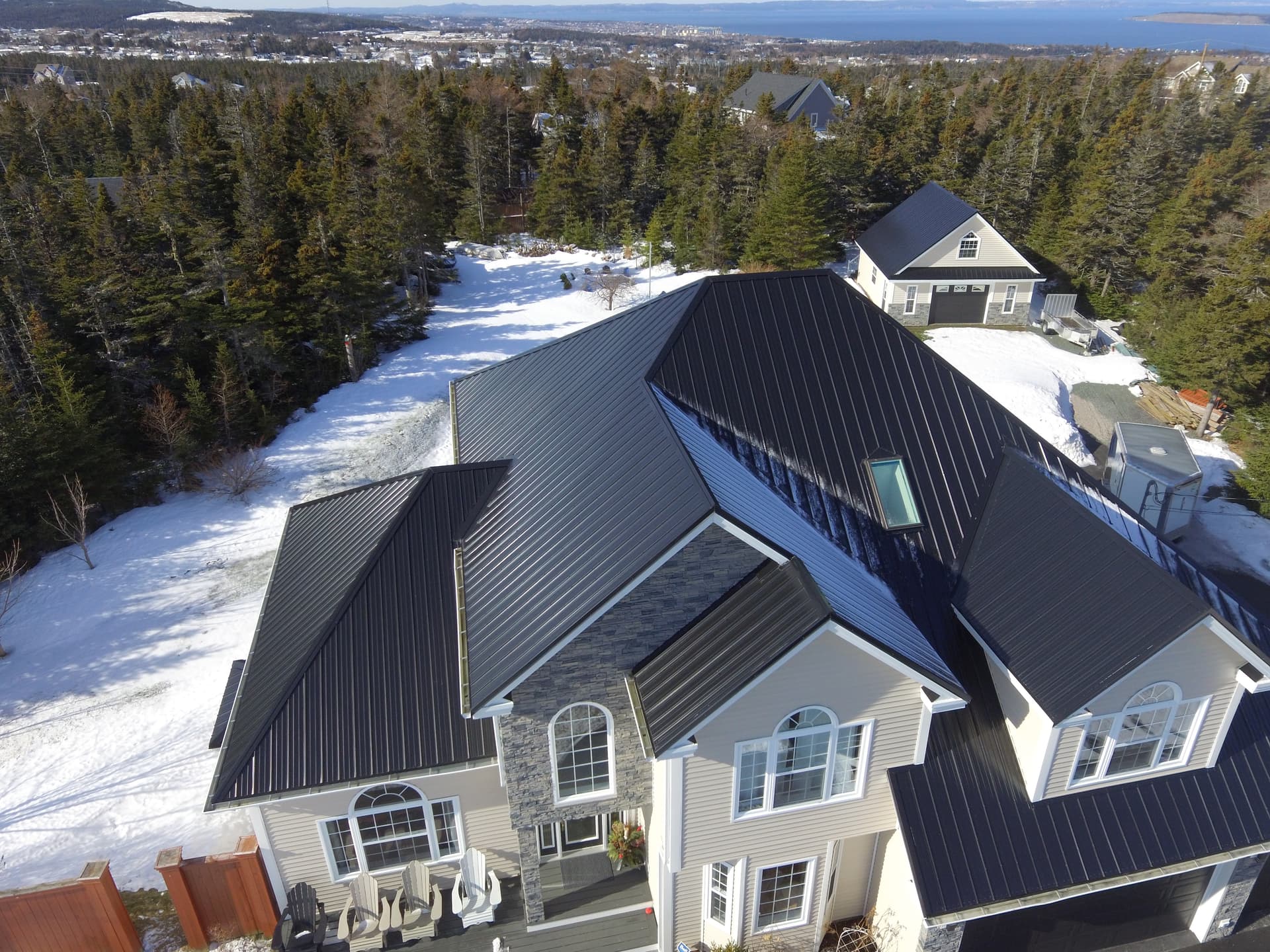 Coastal aerial view of executive estate with black metal roof and ocean background